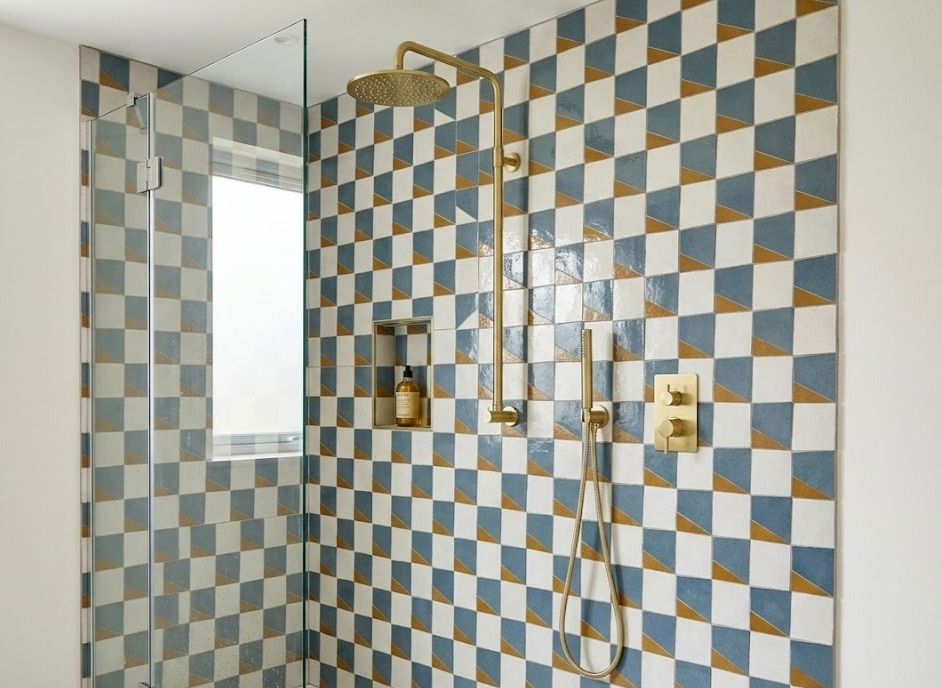 Blue, ochre and white geometric zellige shower wall with brass fittings